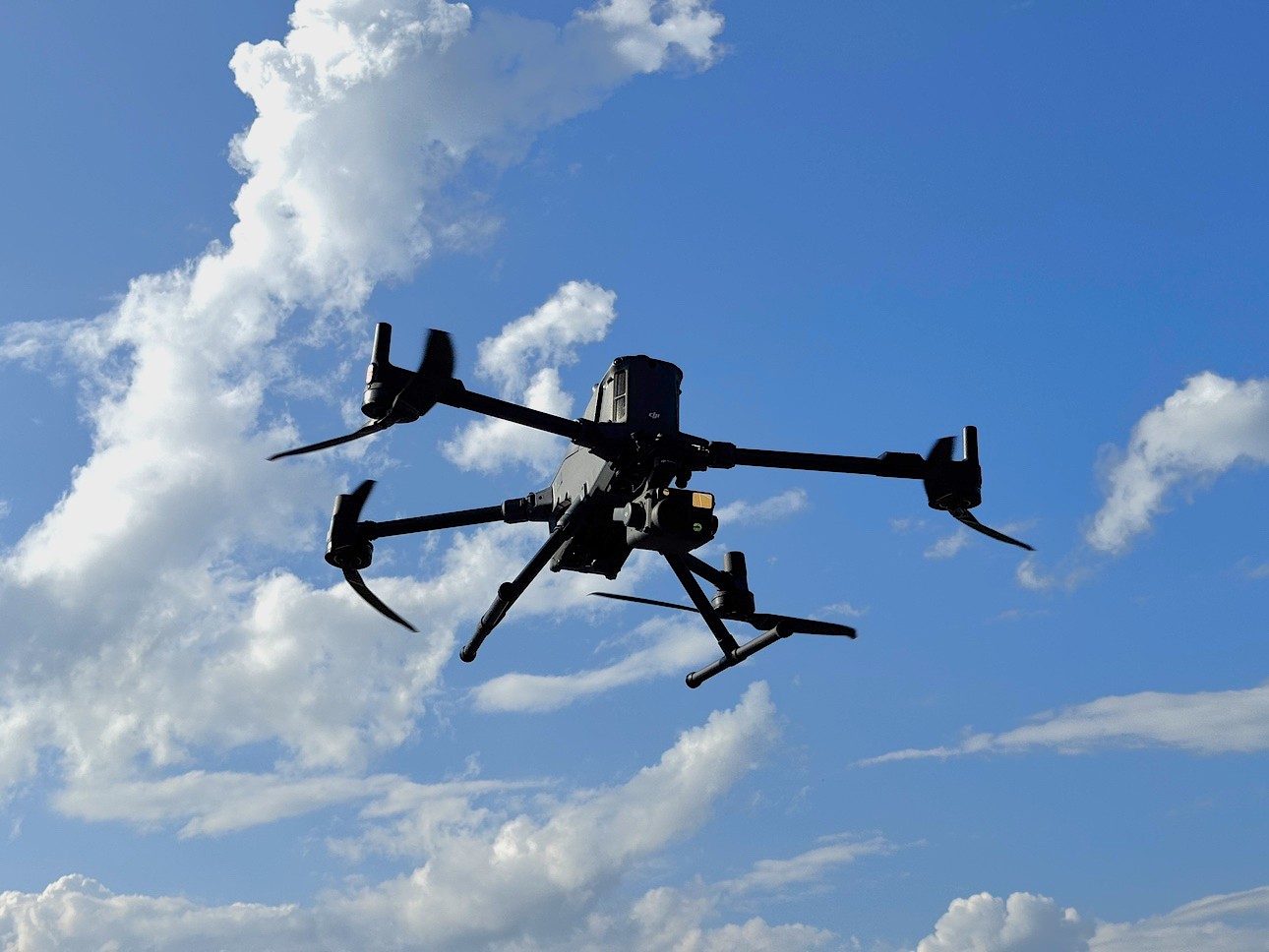 青空を飛ぶ DJI Matrice 400 RTK。機体の下に赤外線カメラ Zenmuse H30T を搭載している