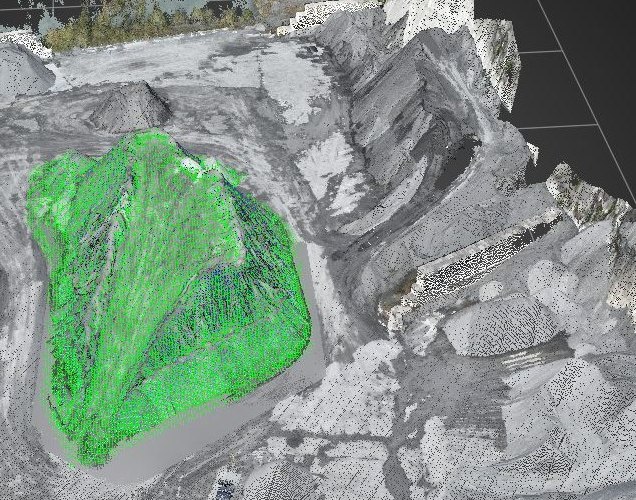 グレーの点群で再現された採石場の解析画面。土量を算出する範囲の土砂の山だけが緑のメッシュで塗り分けられている