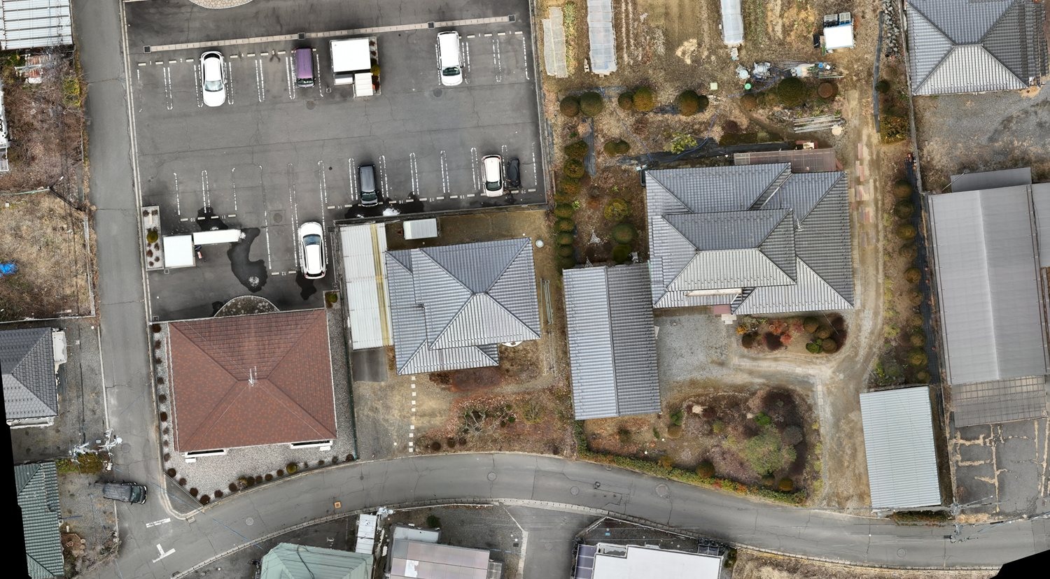 上空から真下に向けて撮影した写真をつなぎ合わせ、歪みを補正したオルソ画像。駐車場に並んだ車、瓦屋根の住宅、生け垣、ビニールハウス、道路が真上から判読できる