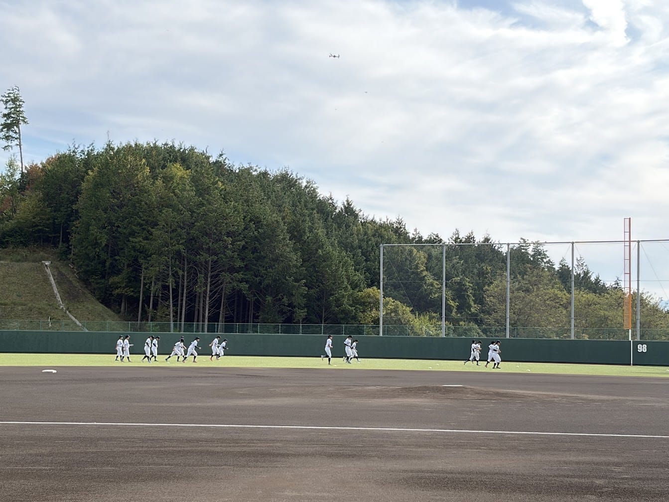 外野を走る選手たちと、上空を飛ぶDJI Mavic 4 Pro